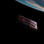 Rendered scene of the AYANEO AG01 floating in space above Earth, emphasizing its "Starship" theme and sci-fi design aesthetic.